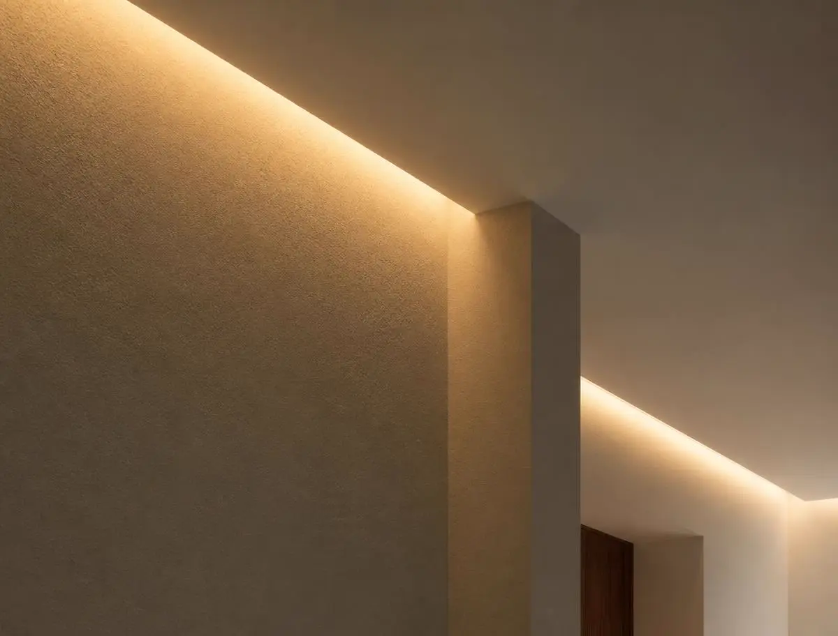 Warme Lichtlinie, die an einer verputzten Wand und einer Deckenkante entlangläuft